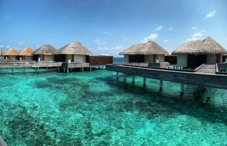 Villas con techo de paja sobre un arrecife de aguas cristalinas en un resort de Maldivas