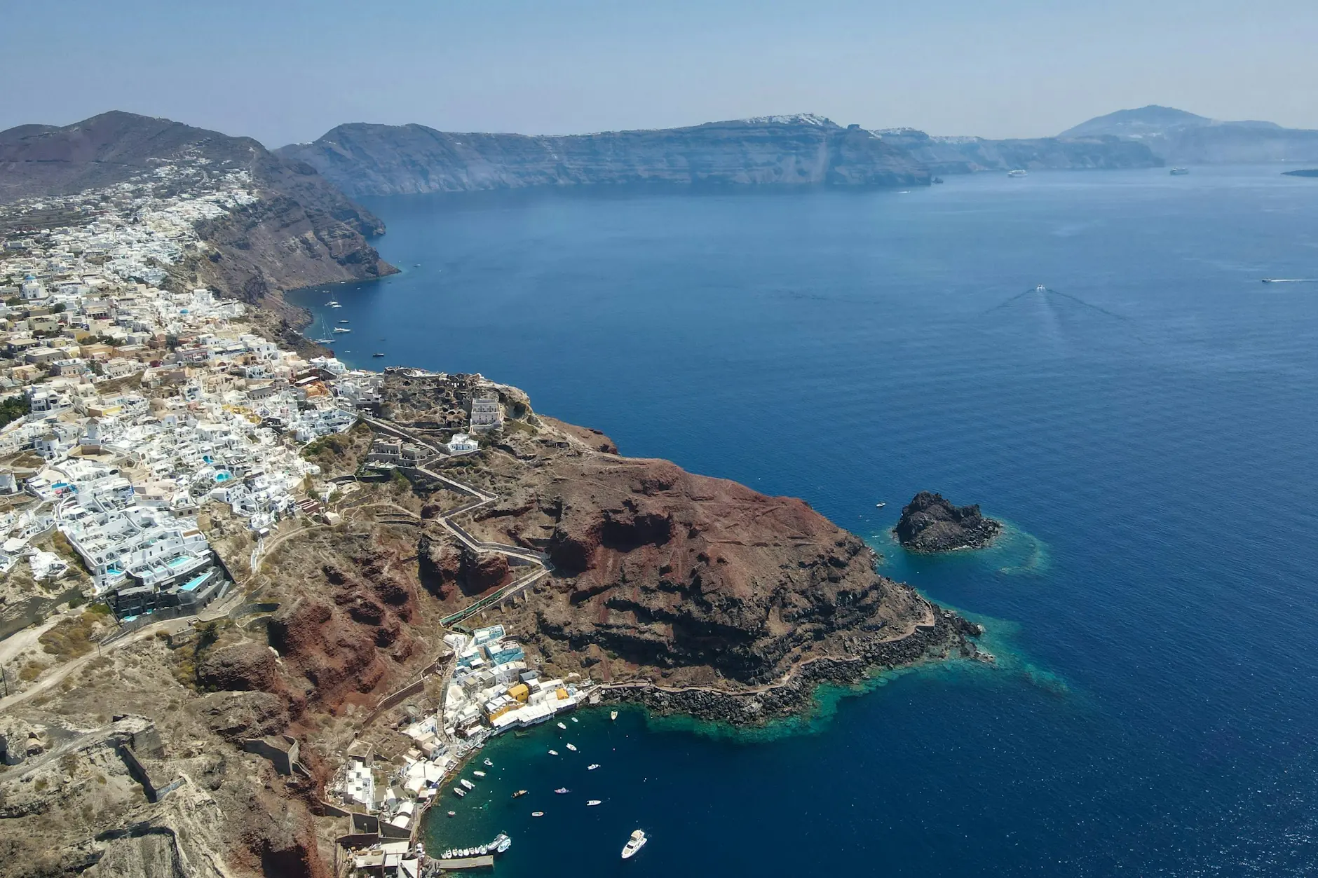 Vista aérea de las casas blancas de Oia y la bahía de Ammoudi sobre la caldera de Santorini
